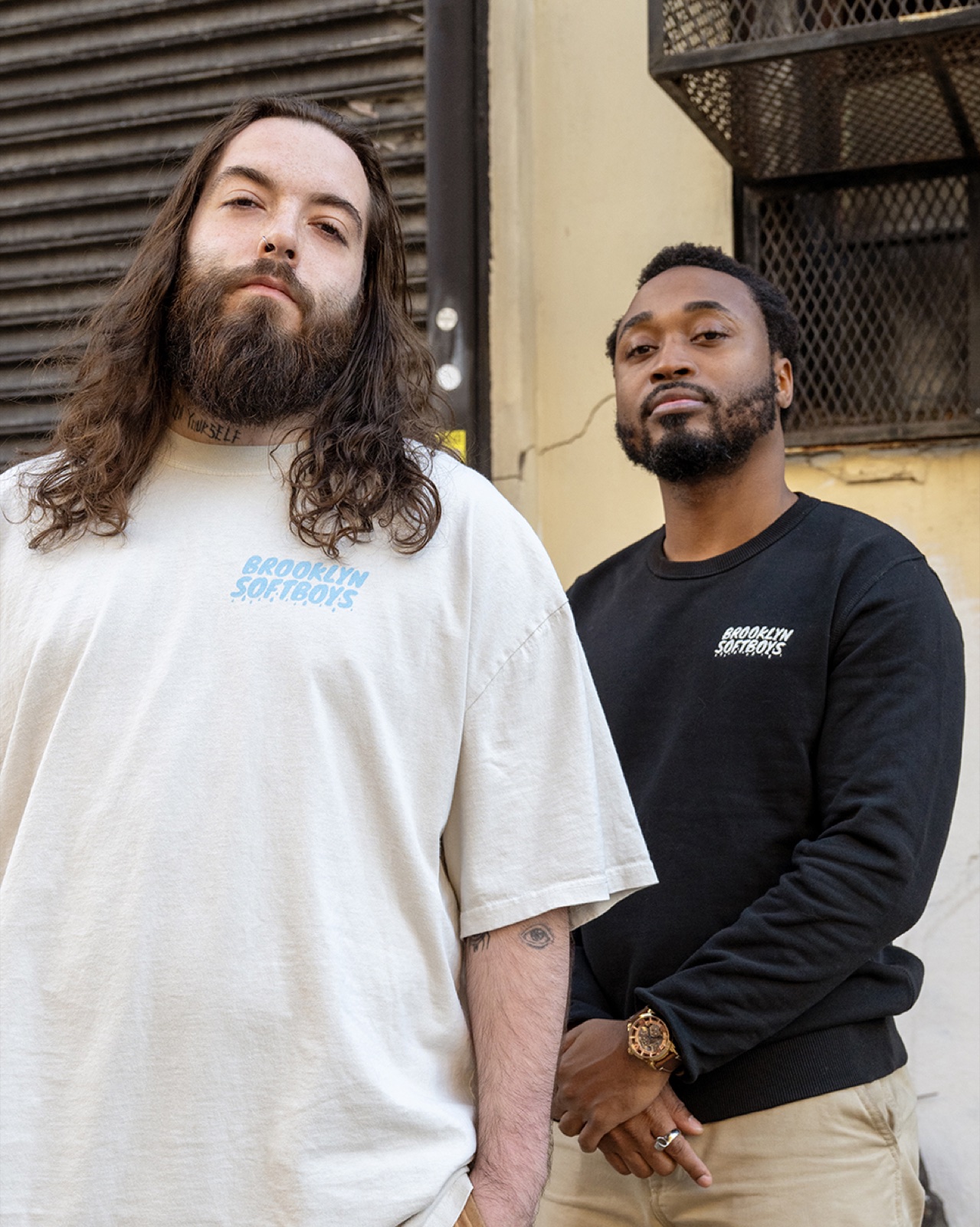 Two models in Brooklyn SoftBoys apparel — cream tee and black crewneck — on a New York street.