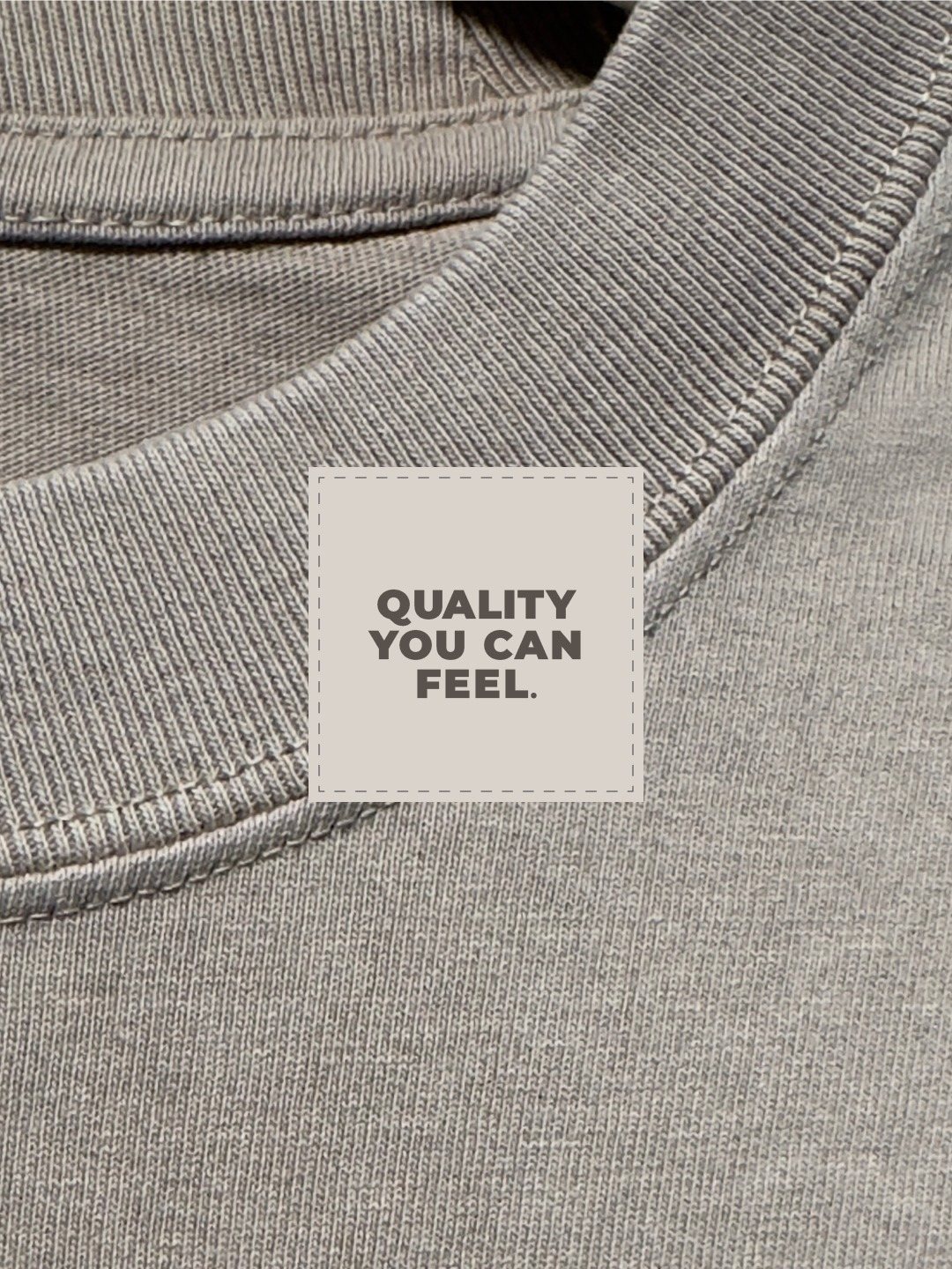 A woven neck label reading Quality You Can Feel, sewn inside the collar of a washed tee.
