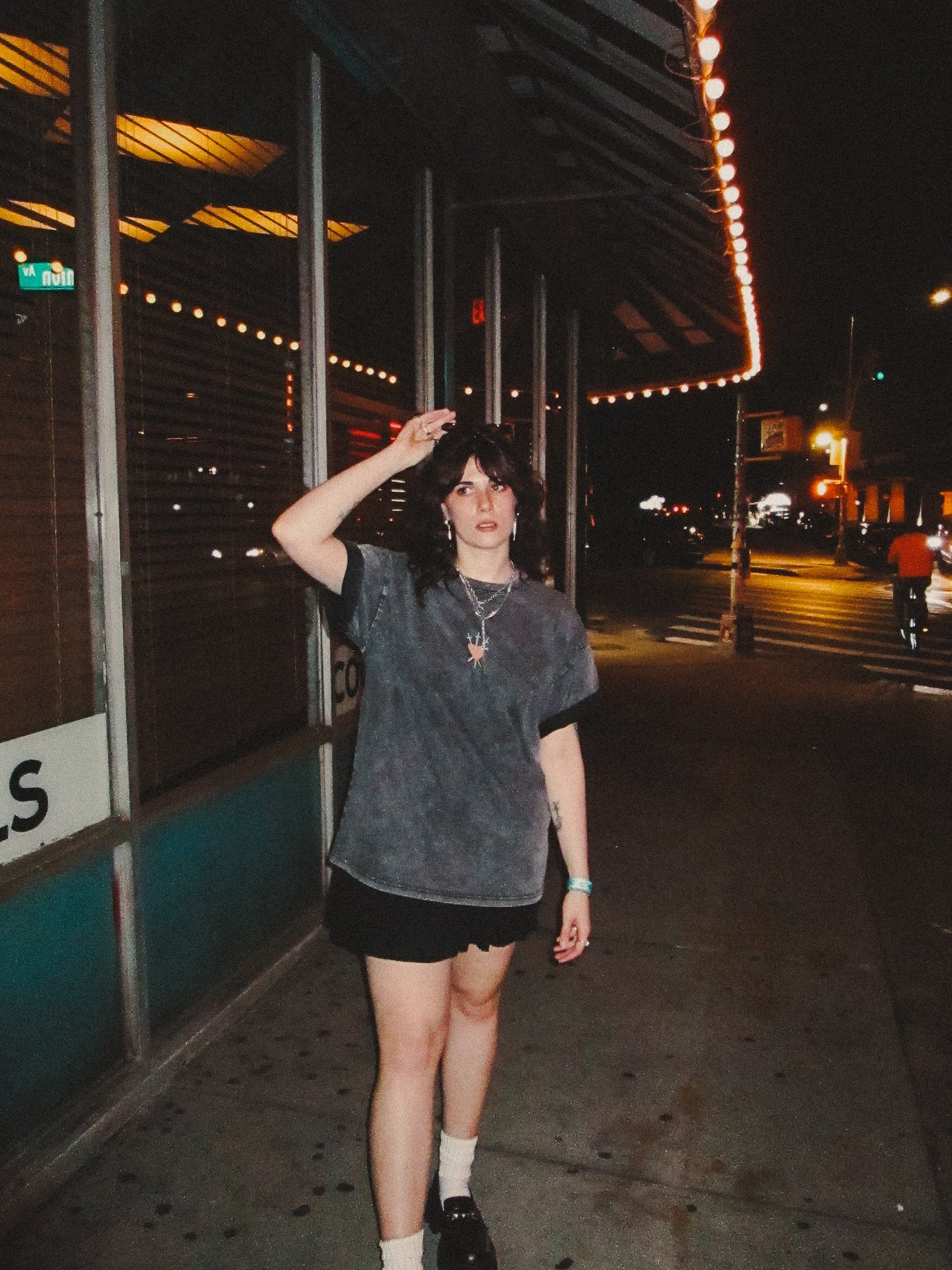 Model walking under a lit marquee at night in the Brooklyn SoftBoys tee.
