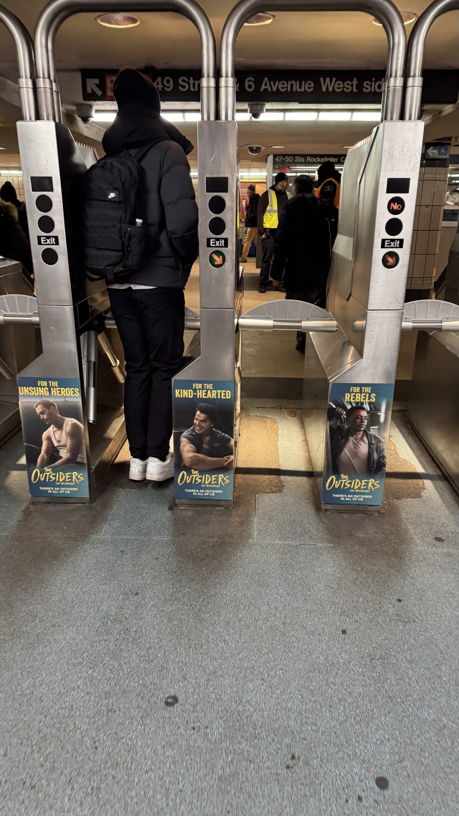 Closer view of the wrapped turnstile housings, with the 49th Street and 6th Avenue signage above.